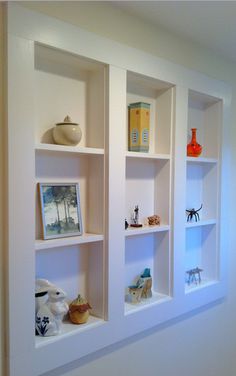 three white shelves with pictures and vases on them in the corner of a room