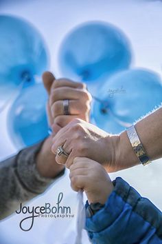 two people holding hands with blue balloons in the background