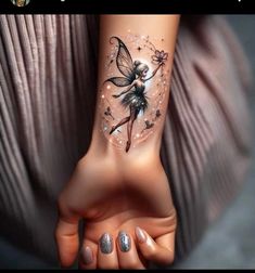 a woman's hand with a tattoo on it that has a flower and a fairy