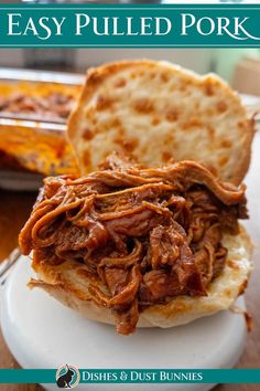 a pulled pork sandwich on a plate with pita bread in the background and text overlay that reads easy pulled pork