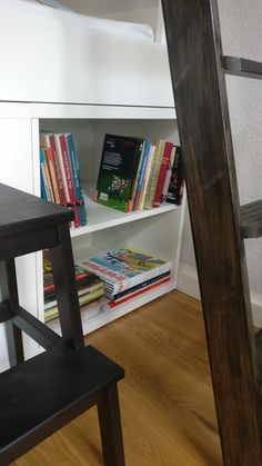 there is a book shelf with books on it and a ladder in the corner next to it