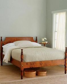 a bed sitting in a bedroom on top of a hard wood floor next to a window