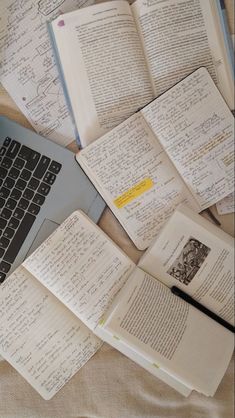 several open notebooks sitting on top of an open laptop computer