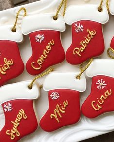 red and white christmas stockings cookies with gold lettering on them sitting on a platter