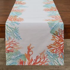 an orange and blue coral print table runner on a wooden table with a white background