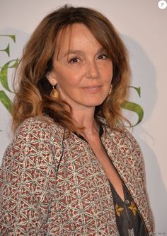 the woman is smiling for the camera in front of a white wall and green letters