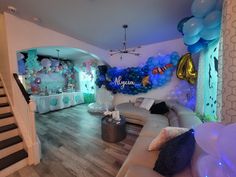 a living room filled with furniture and balloons on the wall next to a stair case