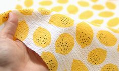 a hand holding a piece of fabric with lemons on it