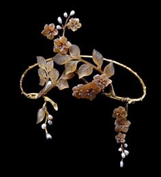 A French Art Nouveau horn, pearl, diamond and gold tiara. Comprising a wire work articulated band sculpted as a twig; and with two asymmetrical horn floral and foliate sprays converging in the front; the flowers with diamond-set stamens and with blister pearl sprays representing the buds. Maker's mark for Paul-Gabriel Liénard, and French control marks, circa 1905.