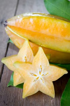 two pieces of fruit sitting next to each other on top of a wooden table with green leaves