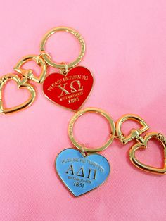 three heart shaped key chains on a pink background