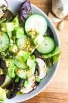 a white bowl filled with cucumbers and other vegetables on top of a wooden table