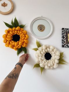 a person's hand reaching for some fake flowers