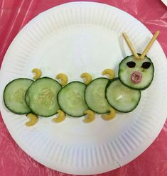 a paper plate with cucumber slices and sticks sticking out of the middle to make a caterpillar