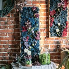 two vases filled with flowers sitting on top of a table next to a brick wall