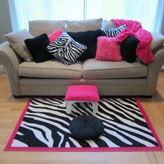 a living room with zebra print rugs and pillows on the couch in front of a window