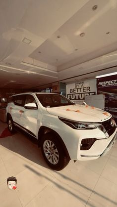 a white suv is parked in a showroom