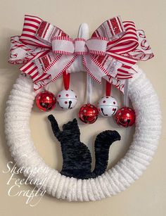 a christmas wreath with red and white ornaments hanging from it's side on a wall