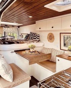 the interior of a camper with white walls and wood ceilinging, bed in center