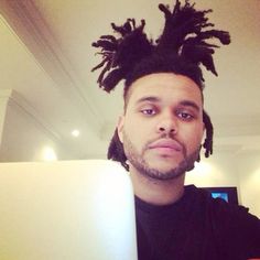 a man with dreadlocks on his head is looking at the camera while using a laptop