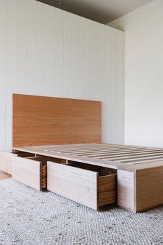 a bed with two drawers on the bottom and one at the footboard, in a room with white walls