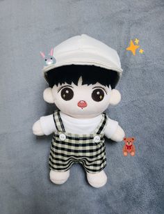 a small stuffed animal wearing overalls and a white hat on top of a blue blanket