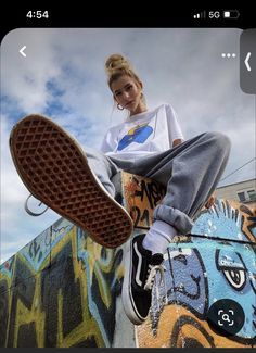 a woman sitting on top of a skateboard next to a wall covered in graffiti