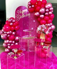 pink and purple birthday decorations on display in front of a large balloon arch with happy birthday written on it