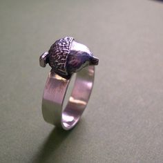 "From little things can GIANTS grow!! You get the idea! The acorn on this piece has been cast, and then silver soldered to its fabricated shank. The finish is brushed ,with a slight antiquing. The shank, or band measures about 5mm, or just under 1/4\". It is a potentially inspiring ring! This piece can also be done in a high polish if desired. Made to order." Silversmithing Jewelry, Silver Oak, Tree Ring, Tree Rings, Oak Tree, Ring Silver, Rings Statement, Little Things, Statement Rings