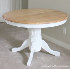 a white table with a wooden top in the corner of a living room or dining room