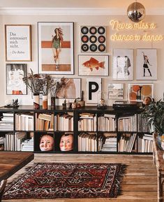 a living room filled with lots of books and pictures on the wall next to a table