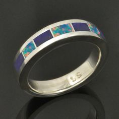 a ring with blue and white opal inlays on the inside of it