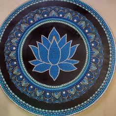 a decorative blue and black plate with a flower design on the center, sitting on a table