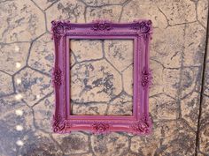 a purple frame sitting on top of a stone floor next to a wall with cracks in it