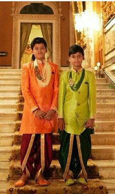 two young boys dressed in colorful clothing standing on stairs