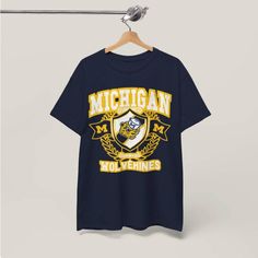 Vintage Michigan T-shirt, University of Michigan Tee, Retro Varsity short sleeve shirt, Michigan University Wolverines, college football and basketball short sleeve. This is the cutest unisex shirt to wear for any occasion, but especially on game days!  ❇ Colors * Black * Navy * White * Dark Heather (Gray)  * Dark Chocolate ❇ The Crewneck * Gildan Heavy Cotton Tee * Medium fabric (5.3 oz/yd² (180 g/m consisting of 100% cotton * Classic and relaxed fit with crew neckline * Made using 100% US cotton that is ethically grown and harvested. Gildan is also a proud member of the US Cotton Trust Protocol ensuring ethical and sustainable means of production. This blank tee is certified by Oeko-Tex for safety and quality assurance. ❇ Shipping & Production We offer FREE shipping on your order, with n Collegiate Graphic T-shirt For Fan Merchandise, College Fan Apparel T-shirt With Team Name, School Spirit Short Sleeve T-shirt With Letter Print, Collegiate T-shirt For Football Season Fan Merchandise, Varsity T-shirt With Team Logo For Football Season, Collegiate Style T-shirt For Football Season Fan Merchandise, Collegiate Style T-shirt For Football Season, College Football Season Team Logo T-shirt, College Sports Season Logo Print T-shirt