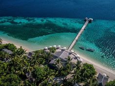 an aerial view of the beach and water with boats docked at one end, surrounded by palm trees