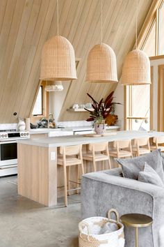 an open kitchen and living room area with wood paneling on the walls, white counter tops and chairs