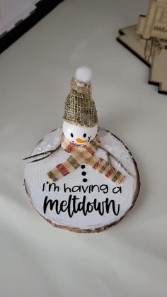 a snowman sitting on top of a wooden slice with the words i'm having a meltdown written on it