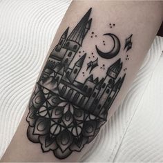 a black and white photo of a castle tattoo on the right arm, with a crescent moon above it