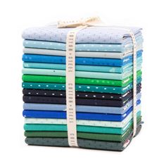 a stack of folded fabric with a measuring tape on top of it, all in different colors