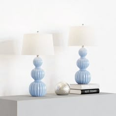 two blue lamps sitting on top of a white shelf