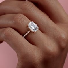 a woman's hand holding an engagement ring with a diamond on the band and side stones