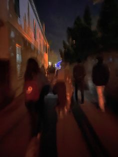 blurry image of people walking down the street at night with buildings in the background