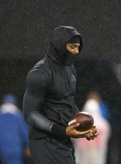 a man holding a football in the rain