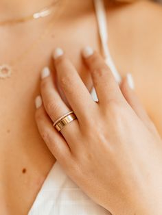 a close up of a woman's hand wearing a gold wedding band and ring