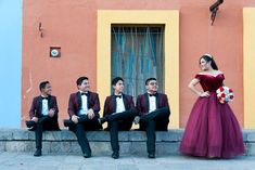 a group of people in tuxedos sitting on a ledge