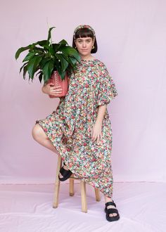 a woman sitting on a stool holding a potted plant