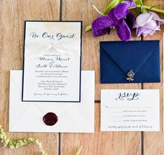 the wedding stationery is laid out on top of the wooden table with purple flowers