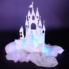 a paper castle sitting on top of a pile of white tissue in front of a purple background